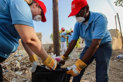 Two people in masks and gloves cleaning up garbage from the street