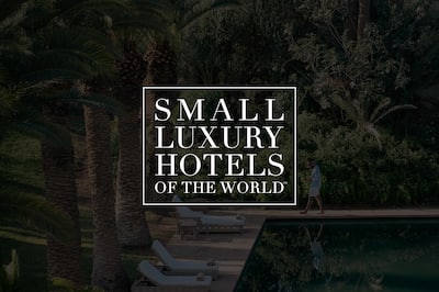 Small Luxury Hotel logo over dark, tinted background of a person walking by a luxurious pool