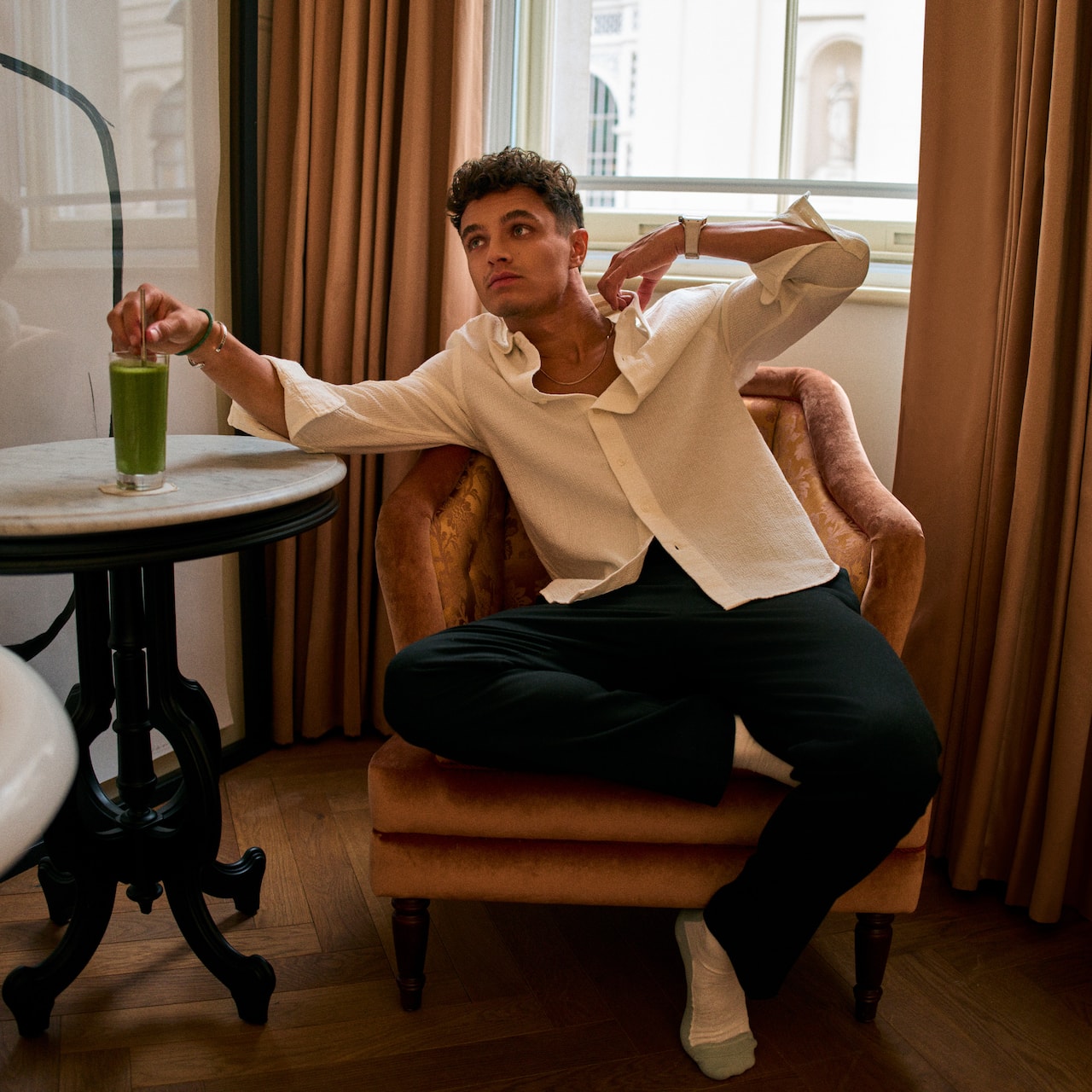 Lando Norris relaxing on chair with green drink