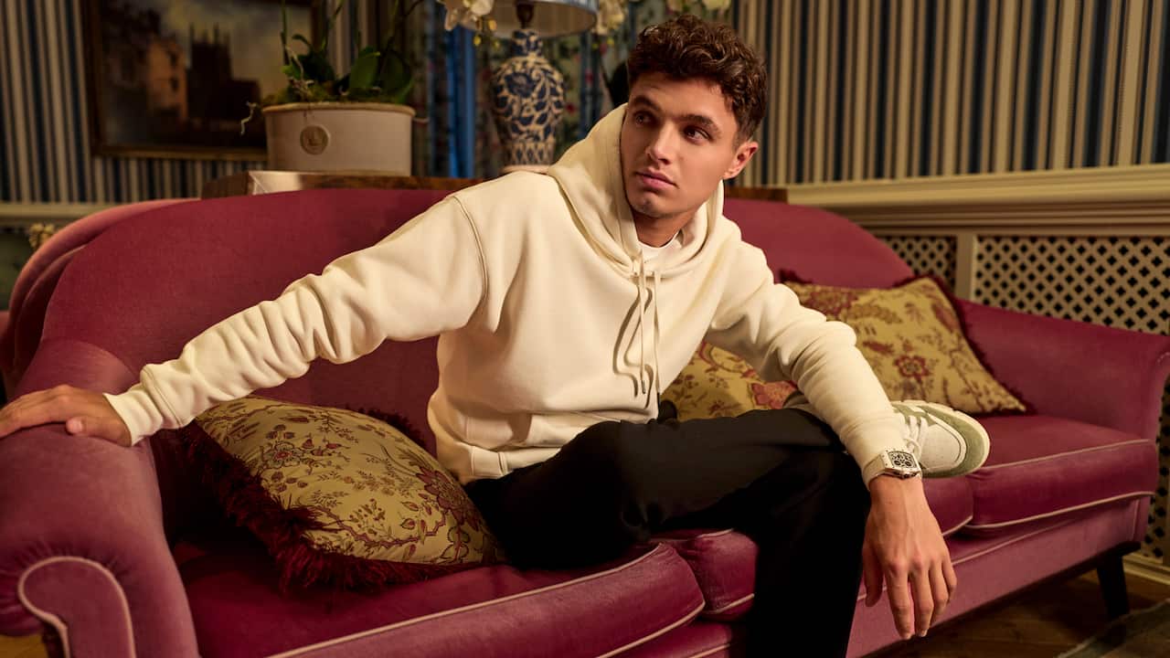 Lando Norris relaxing on couch wearing white top