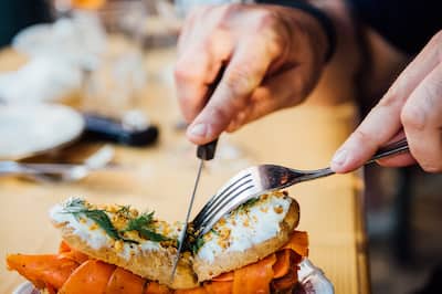 Person cuts sandwish with knife and fork