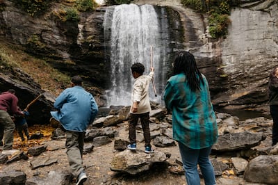 Family standing in rocky area with waterfall in background