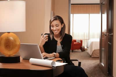 Business woman drinking coffee and working on her laptop