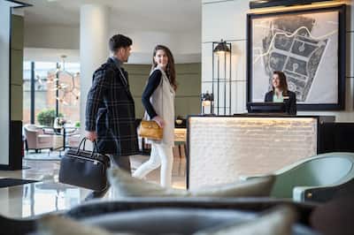 Man and Woman Looking at Each Other, Walking Past Front Desk Team Member