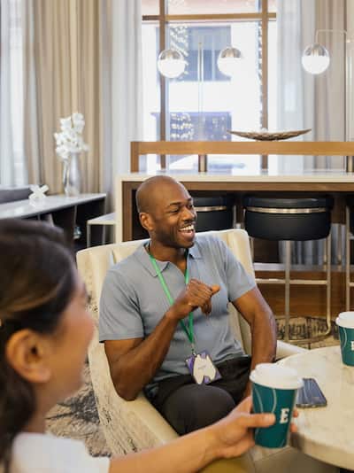 Man and woman smiling and drinking coffee at a meeting