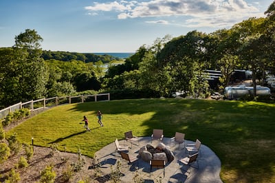 Kids playing on lawn area with fire pit and chairs