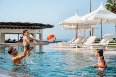 family playing in outdoor pool