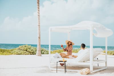 two people sitting on a sun lounger on the beach