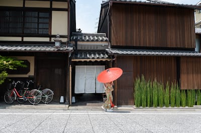 Building with woman walking in front with an parisol