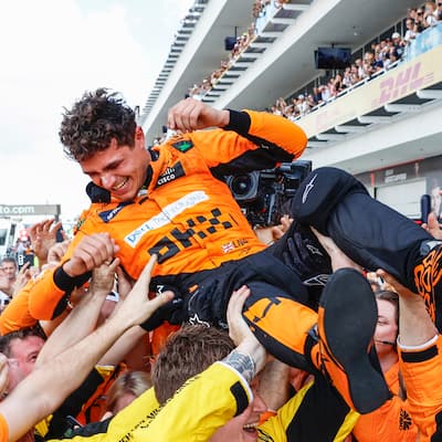 Lando Norris being lifted in the air and celebrating with McLaren racing after winning the Miami Grand Prix