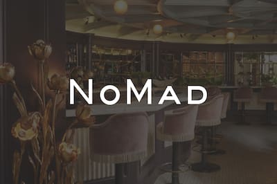A white NoMad logo over image of a hotel bar