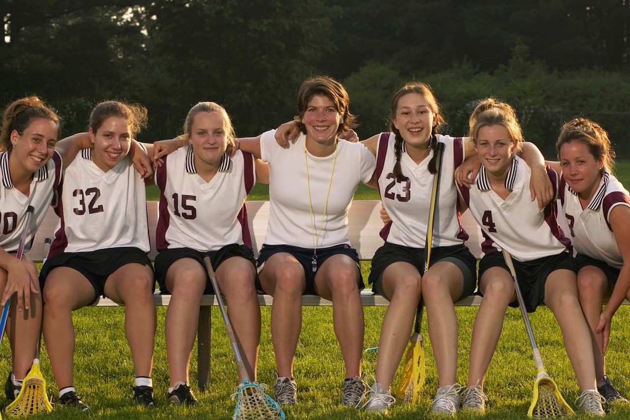 A girls' lacrosse team posing for a picture with their coach.