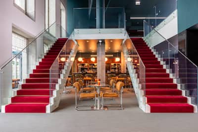 Lobby area with grand double staircase with red carpets and tables and chairs