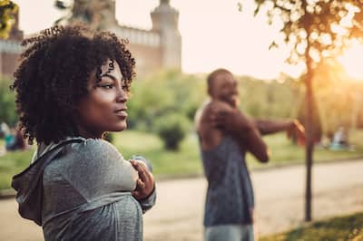 African American woman and man stretching before a run in a park