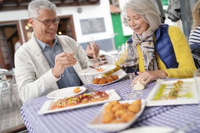 Attractive senior couple eating tapas outdoors.