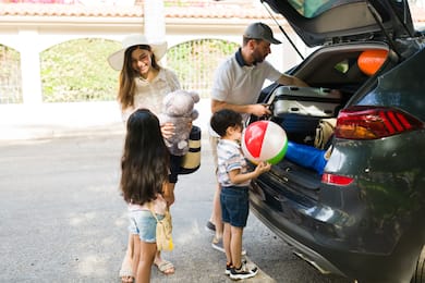 Family unpacks luggage from car at hotel arrival
