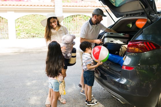 Family unpacks luggage from car at hotel arrival 