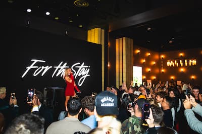 Paris Hilton performing on a stage in front of a For The Stay sign with a large crowd
