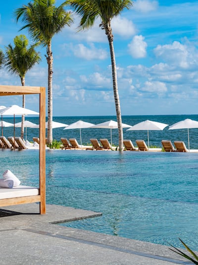 View of pool with cabana and loungers overlooking the ocean